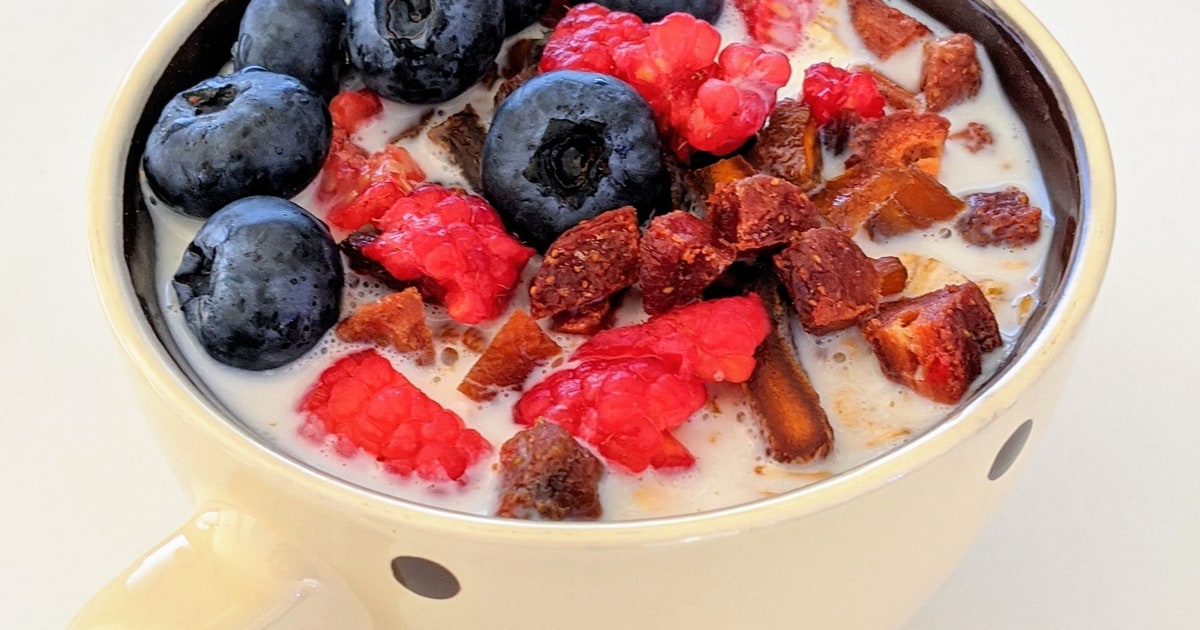 A yogurt breakfast bowl topped with blueberries, raspberries, and dried fruit.